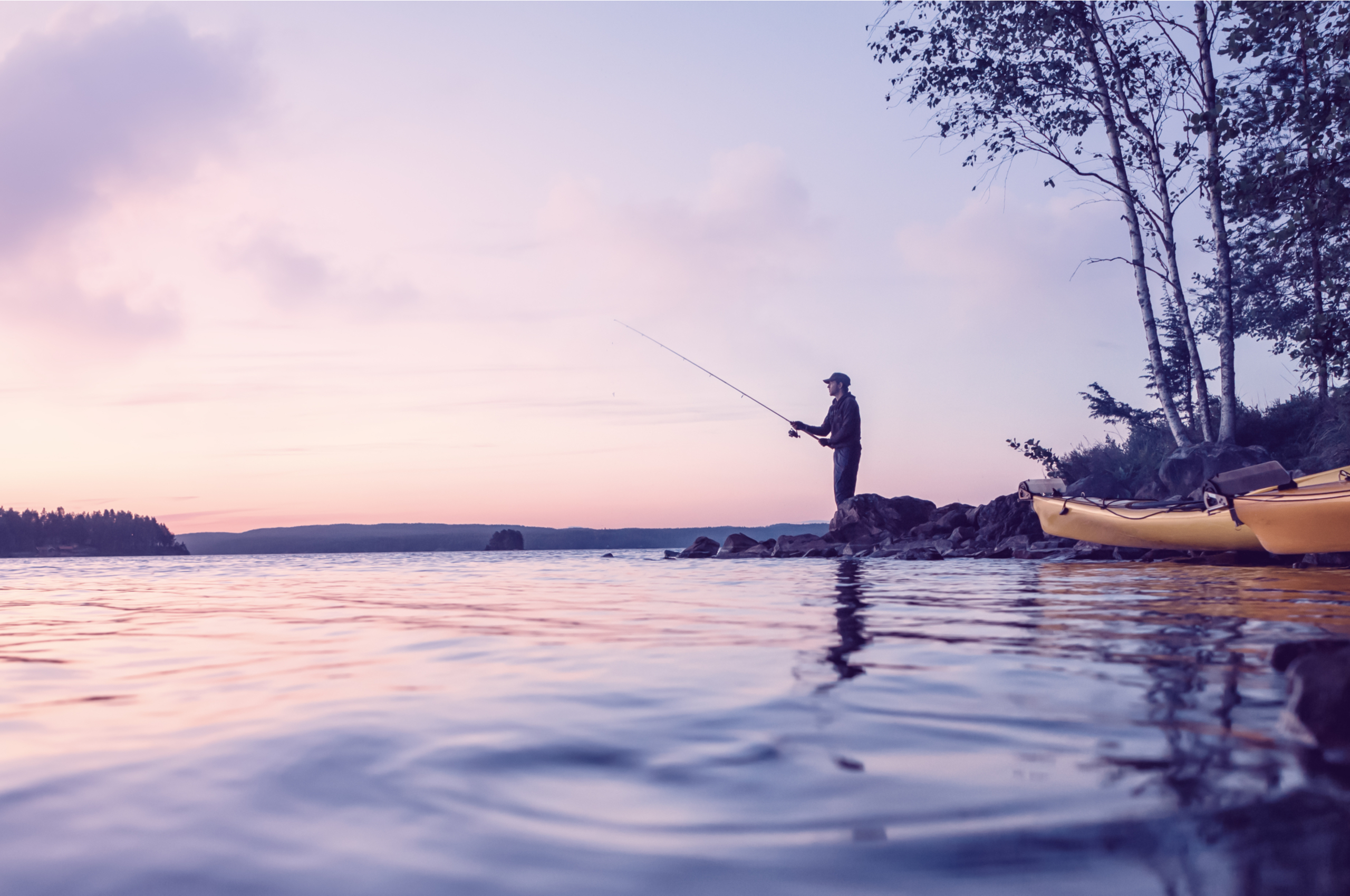 a man fishing on a lake after sunset