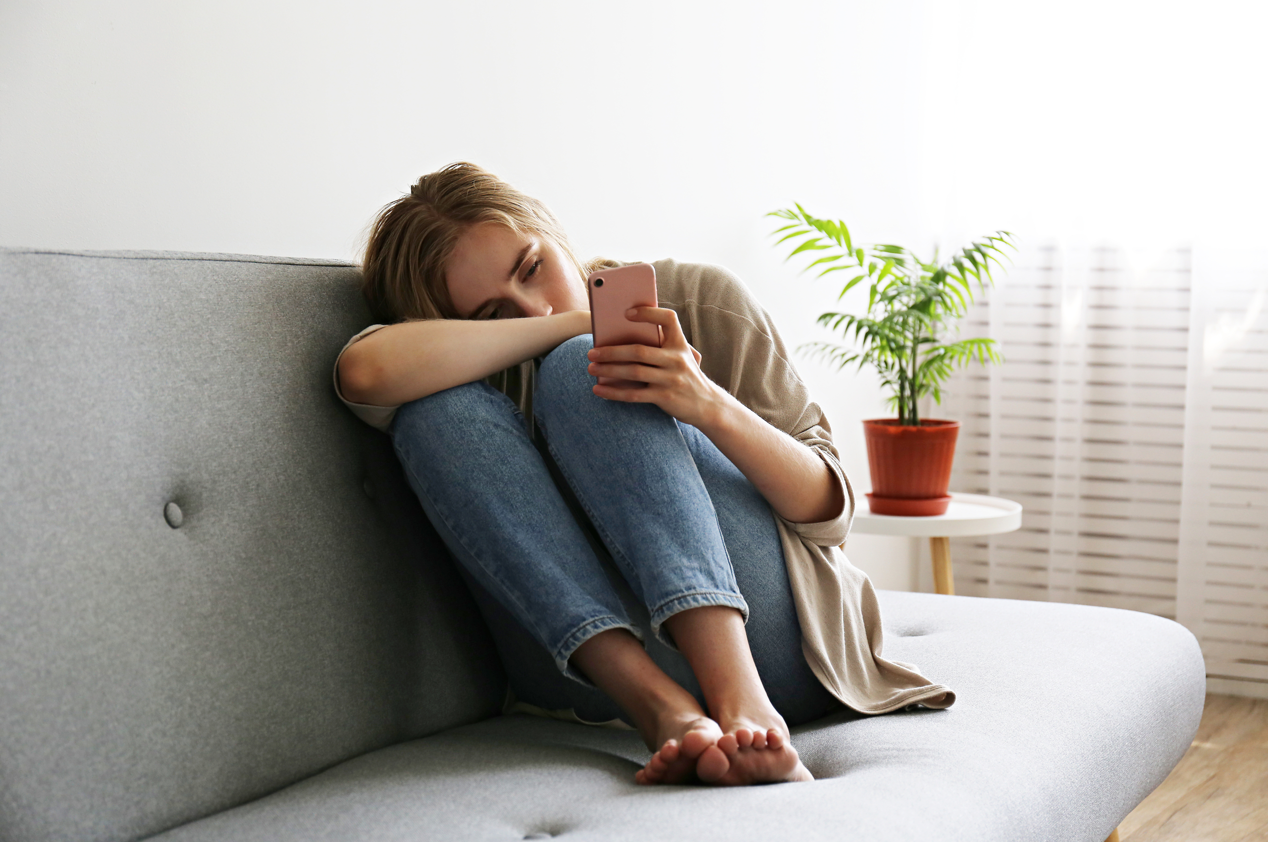 young woman looking sad while looking at her phone