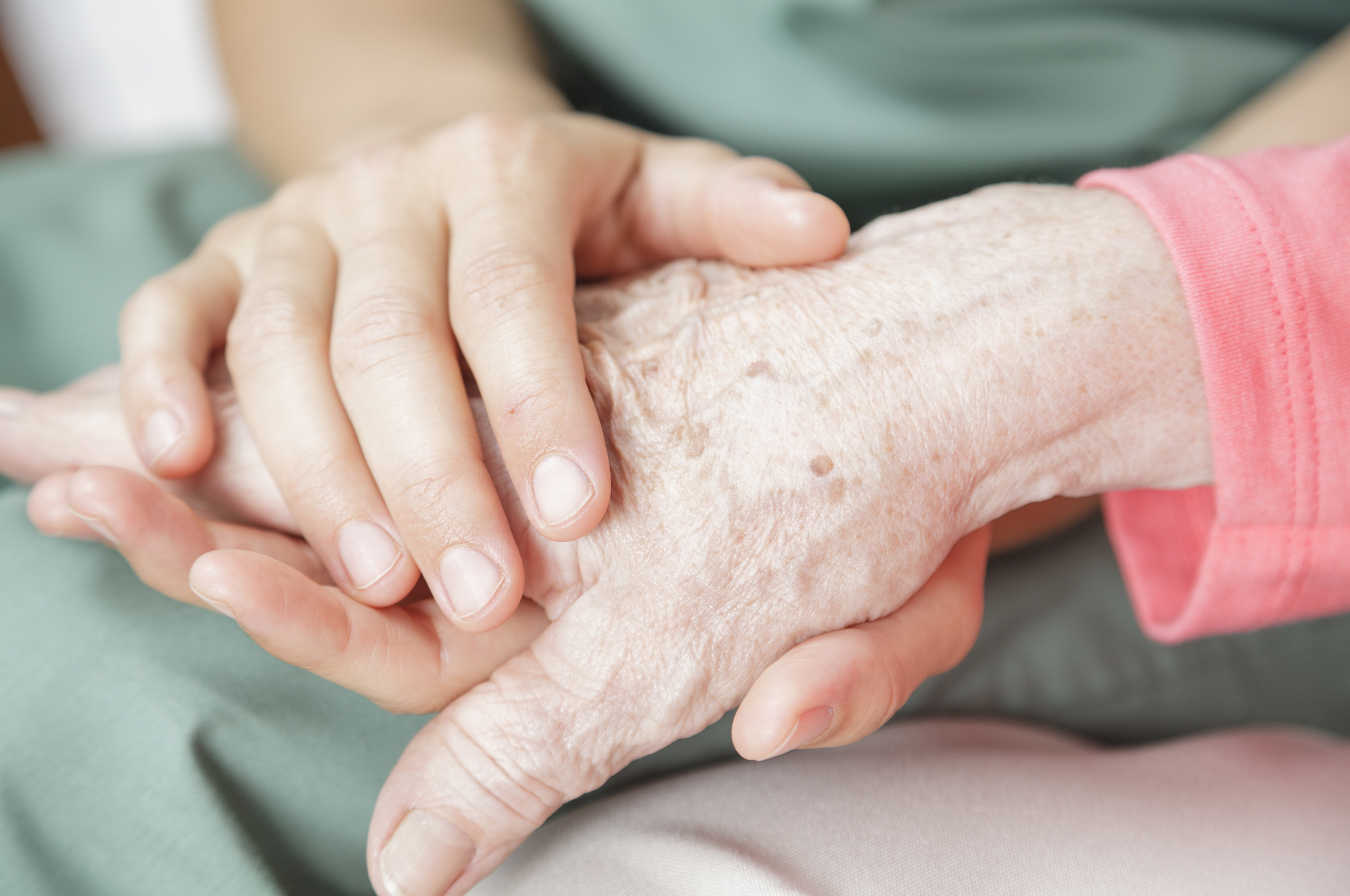 close up of a younger person holding an older person’s hand