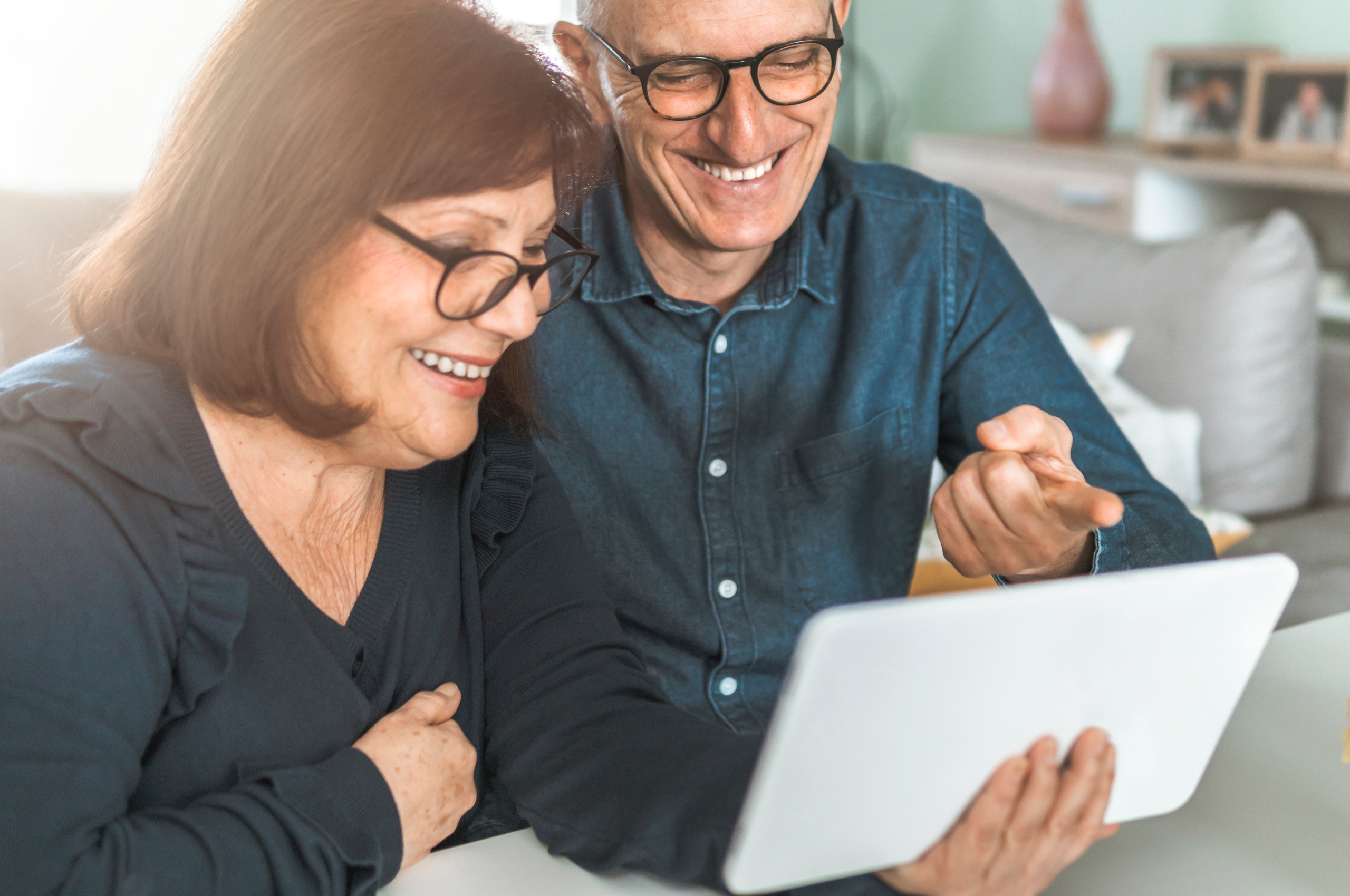 middle-aged couple looking at a tablet and smiling