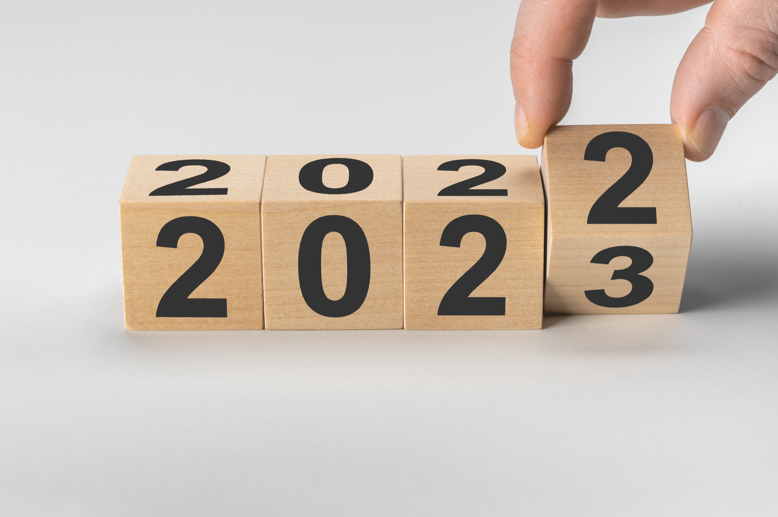 person changing a wooden block calendar from 2022 to 2023