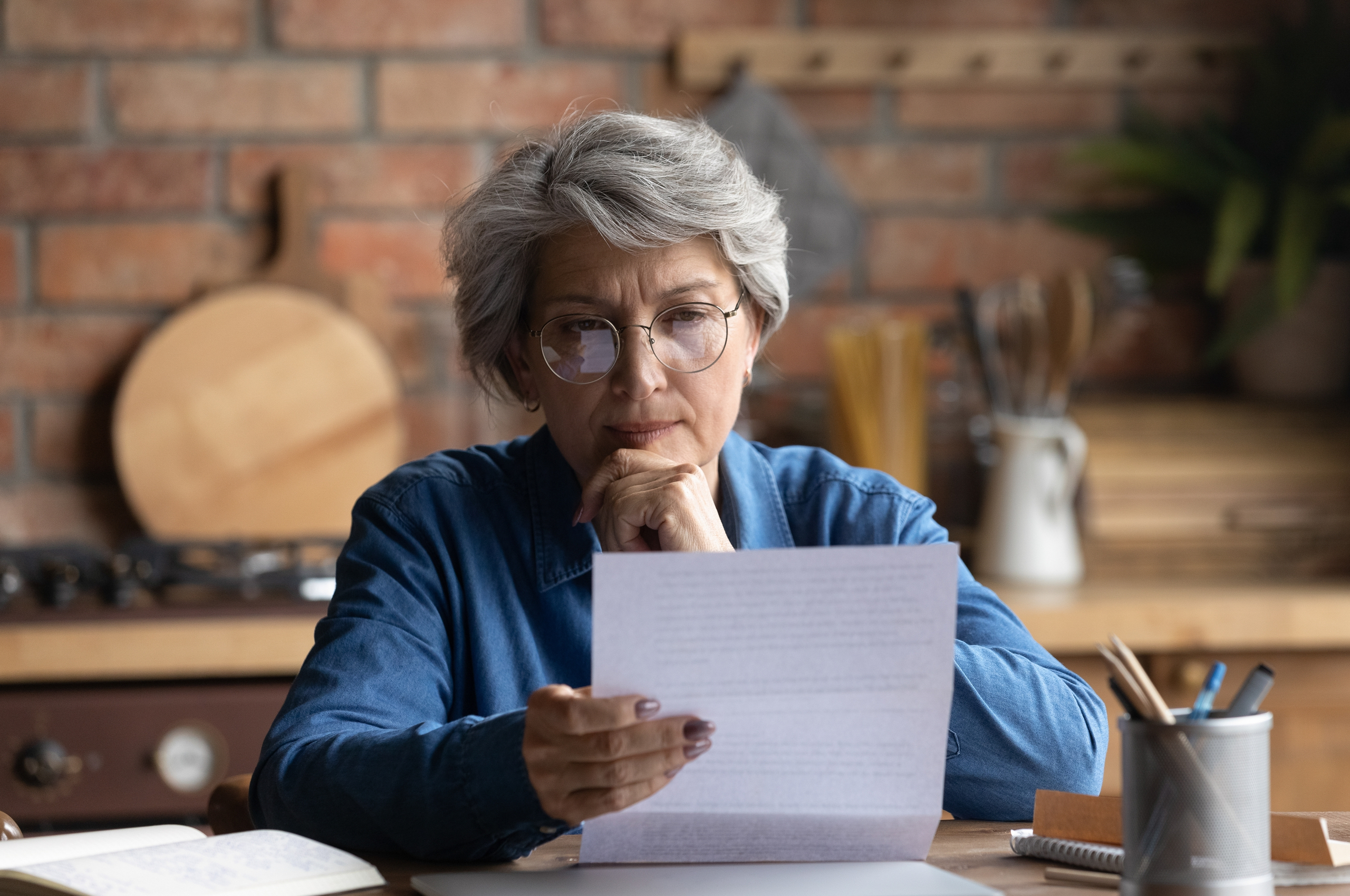 A middle-aged woman looks thoughtfully at a document